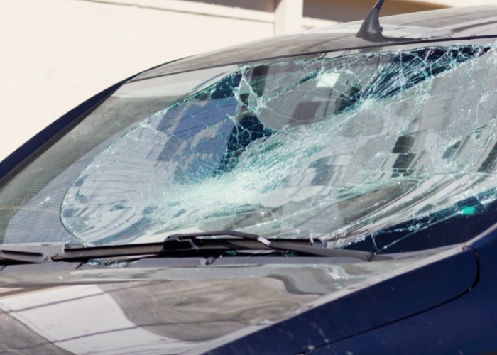 Shattered windshield on a vehicle, showing extensive cracks and damage, in need of replacement.